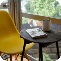 写真:テーブルの上にコーヒーと本が置いてあります。奥に猫がいます。